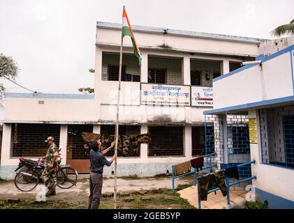 Der Schulleiter hisste am Unabhängigkeitstag die indische Nationalflagge ohne Schüler nach den Standards der vergangenen Jahre vor COVID – 19. Die ländliche Grundschule an der Grenze zwischen Indien und Bangladesch war ein Quarantänezentrum für die indische Grenzschutztruppe (BSF), und die Schüler haben keine Erlaubnis, die Schule zu betreten. Nabin Nagar, Westbengalen; Indien. Stockfoto