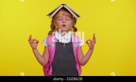 Teen Mädchen in der Schuluniform das Buch auf den Kopf, meditierend, entspannend mit konzentrierten Gedanken Stockfoto