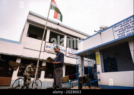 Der Schulleiter hisste am Unabhängigkeitstag die indische Nationalflagge ohne Schüler nach den Standards der vergangenen Jahre vor COVID – 19. Die ländliche Grundschule an der Grenze zwischen Indien und Bangladesch war ein Quarantänezentrum für die indische Grenzschutztruppe (BSF), und die Schüler haben keine Erlaubnis, die Schule zu betreten. Nabin Nagar, Westbengalen; Indien. Stockfoto