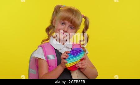 Fröhliche Schüler Mädchen spielen mit Pop es sensorische Anti-Stress-Spielzeug Kind drückt auf squishy Blasen Spiel Stockfoto