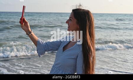 Junge Frau beim Selfie am Meer. Stockfoto