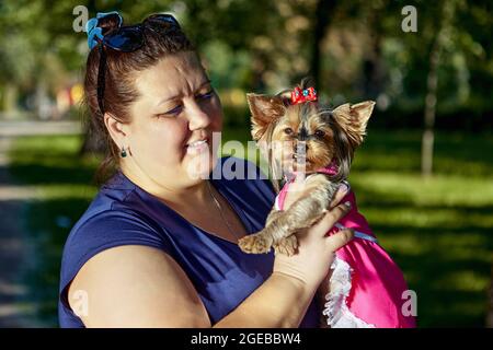 Fat Woman hält Terrier im Park während des Gehens. Stockfoto