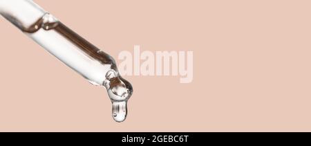 Kosmetik Tropfer, fallen Tropfen aus nächster Nähe. Nahaufnahme der kosmetischen Pipette mit Tropfen ätherischem Öl, Serum mit Peptiden auf beigem Hintergrund. Selbstversorgung Stockfoto