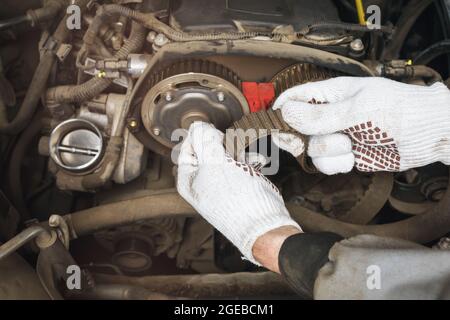 Ein Automechaniker überprüft den Zustand eines alten Zahnriemens auf verschiedene Defekte, Nahaufnahme Stockfoto