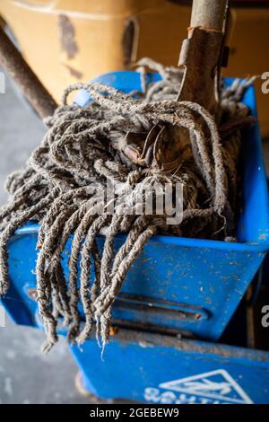 Alter Bodenmopp mit Holzgriff und blauem Wischeimer Stockfoto