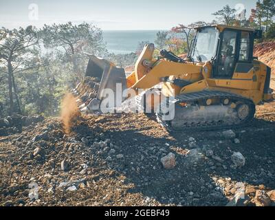 Bulldozer schaufelt Boden bei Straßenbauarbeiten Stockfoto