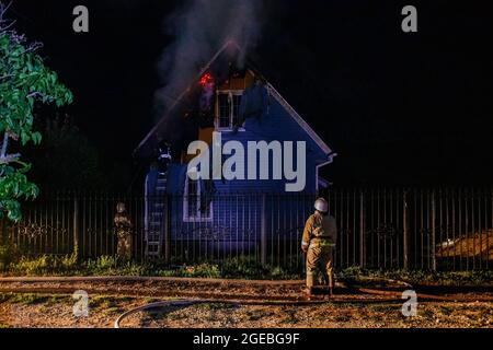 Feuerwehrmänner löschen das Feuer im Landhaus in der Nacht. Stockfoto