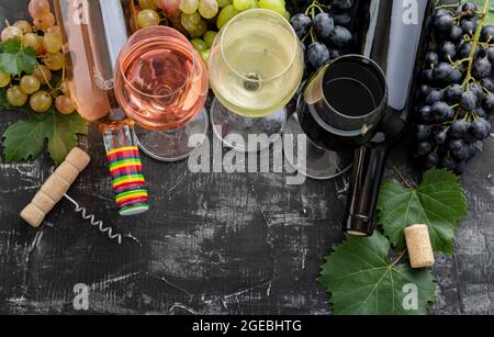 Weißwein Rosé Rotwein in Gläsern Wahl zum Verkosten. Weinsorten in Flaschen. Verschiedene Sorten Trauben. Weinkomposition mit auf dunkel launisch Stockfoto