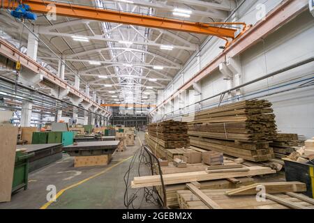 Im Inneren der riesigen Werkshalle mit Holzstapeln für die Herstellung von Formen. Holzarbeiten Herstellung Produktion Industrie. Stockfoto