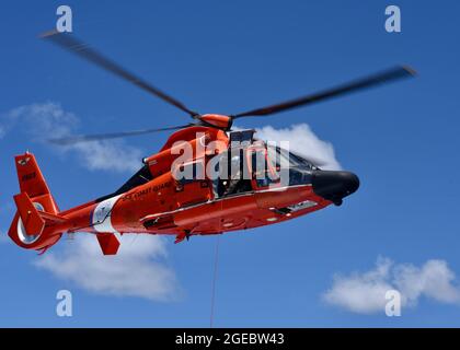 Ein Air Station Barbers Point MH-65 Dolphin Helikopter-Luftbesatzungszug rettet Dummy während einer Multi-Agentur Such- und Rettungsübung vor Kauai, 12. August 2021. Die Dolphin Aircrew holte den Rettungsdummy vom Deck einer Küstenwache Kauai 45-Fuß-Sicherheitsboot-Medium in der Nähe von Port Allen, Kauai. (USA Foto der Küstenwache von Petty Officer 3rd Class David Graham) Stockfoto