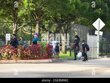 Pembroke Pines, USA. August 2021. PEMBROKE PINES, FLORIDA - 18. AUGUST: Schüler werden von ihren Eltern zur Schule abgesetzt, als sie von der Fakultät begrüßt werden, die sie am Mittwoch, den 18. August, zum ersten Unterrichts-Tag an der Broward County School in Pembroke Pines, Florida, USA, eintrifft. 2021. Das Florida State Board of Education sagte, dass es trotzige Schulbezirke zwingen würde, sich an den Executive Order des republikanischen Gouverneurs Ron DeSantis zu halten, der es ihnen verbietet, Studenten zu verbieten, Masken zu tragen, um einen Anstieg der Covid-19-Fälle zu verlangsamen. (Foto von JL/Sipa USA) Quelle: SIPA USA/Alamy Live News Stockfoto