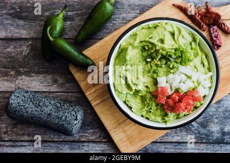 Schüssel mit Guacamole neben frischen Zutaten auf einem Holztisch in Mexiko Stockfoto