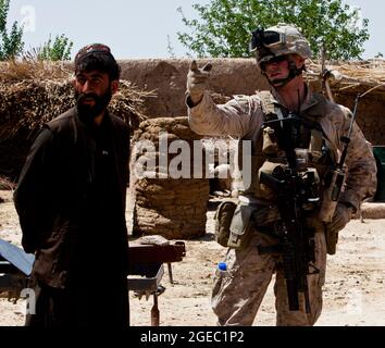 PATROUILLENBASIS FULOD, Provinz Helmand, Islamische Republik Afghanistan - Seaman Orlando C. Farase, ein Korpsmann für das Beratungsteam 4, das der Firma C, 1. Bataillon, 5. Marine-Regiment, angeschlossen ist, verbanden während einer Patrouille in Sangin, Afghanistan, Mai 11, die Hand eines Kindes. Soldaten der afghanischen Nationalarmee vom 2. Tolay, 2. Kandak, führten die Anwesenheitssatrouille durch Sangin und wurden von Marine-Beratern für das Team begleitet, die ausschließlich dort waren, um die ANA-Soldaten zu beobachten und Feedback zu geben. Farase, 22, stammt aus Pensacola, Florida Stockfoto