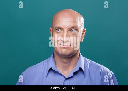 Porträt eines kahlen Mannes auf blauem Hintergrund. Model in den 40er Jahren, blaue Augen und ein blaues Hemd. . Lächelnder Gesichtsausdruck Stockfoto