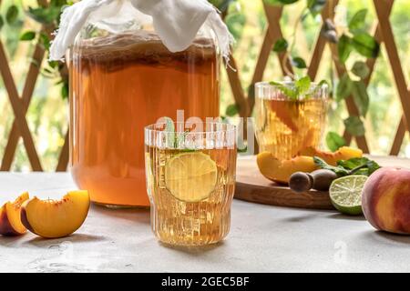 Kombucha-Tee leicht alkoholisches, leicht brausendes Getränk mit Pfirsich und Limette. Hausgemachte Gärung. Probiotisches, gut gesundes Getränk. Stockfoto