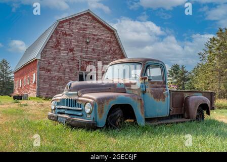 Vintage rote Scheune mit verlassenen Pickup-Truck auf einem Bauernhof auf den Prärien in Saskatchewan Stockfoto