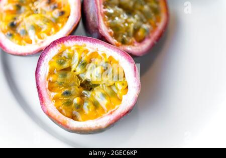 Nahaufnahme, Passionsfrucht, Schnitt halbe Passionsfrucht in weiße Platte. Stockfoto