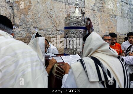 Eine Gruppe religiöser Juden, die mit einer Tora-Schriftrolle an der Klagemauer (alias Kotel) beten, gedenkt Tisha B'AV in Jerusalem, Israel. Stockfoto