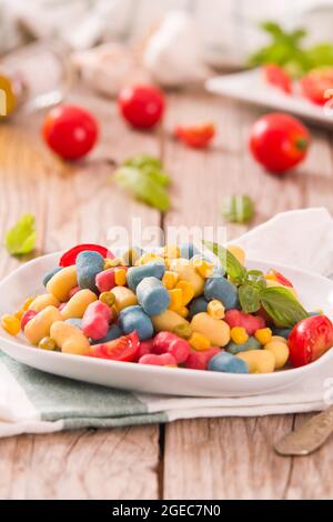 Farbige Gnocchi mit Gemüse und süßem Mais. Stockfoto