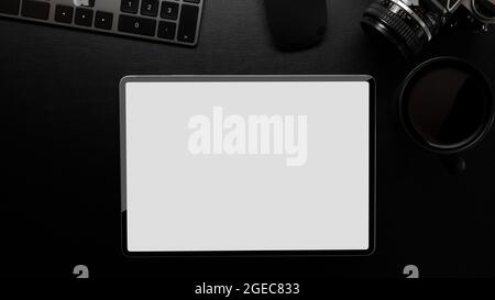 Arbeitsbereich des Fotografen, modernes Tablet-Modell, Kamera, schwarzer Kaffee, Tastatur auf schwarzem Lederschreibtisch, dunkelmodern, schwarze Oberfläche, Draufsicht Stockfoto