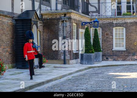 Staycation Idee. Die Coldstream Guards halten eine Waffe in militärischer Kleidung und marschieren vor dem Haus der Königin am Tower of London, Großbritannien. Stockfoto