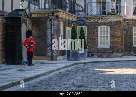 Staycation Idee. Coldstream Guards Wachposten in Militärkleidung mit einer Waffe, die an der Wachtposten-Box vor dem Queen's House am Tower of London UK angebracht ist Stockfoto