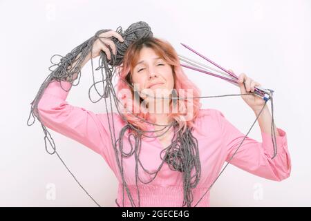 Gestresste Frau mit Wolle und Stricknadeln in ihrem Körper verwickelt Stockfoto