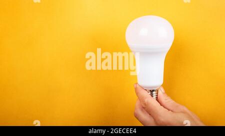 led-Glühlampe in der Hand mit Kopierraum auf gelbem Hintergrund. Stockfoto