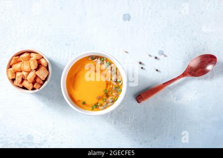 Butternut-Kürbissuppe mit schwarzem Pfeffer, darüber liegende flache Lage auf einem grauen Schieferhintergrund mit Kopierraum geschossen Stockfoto