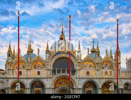 Hauptfassade der Markusplatz-Kathedrale, Venedig. Italien. UNESCO-Weltkulturerbe, blauer Himmel und Wolken. Dekorationen, Mosaiken, Marmorschnitzereien, Statuen. Stockfoto