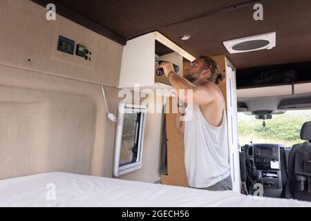 Mann, der einen kleinen Schrank in einen Wohnwagen einzieht Stockfoto