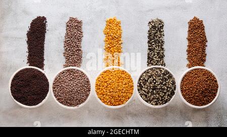 Split black gram, Split bengal gram, turkish gram, Tau gram, ganze schwarze Linsen, Hülsenfrüchte und Körner auf Löffeln Stockfoto