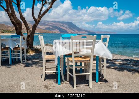 Tische mit Stühlen in der traditionellen griechischen Taverne in Kissamos an der Küste. Kreta, Griechenland Stockfoto