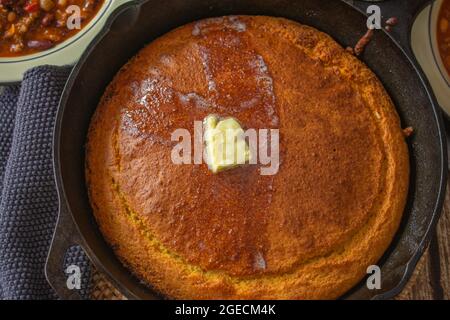 Hausgemachtes frisch gebackenes Maisbrot in einer rustikalen gusseisernen Pfanne mit geschmolzener Butter Stockfoto