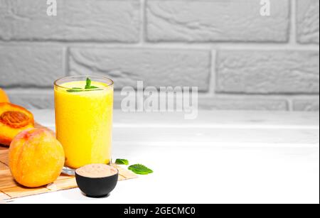 Smoothie mit Pfirsich und Minzblatt mit Stück Tuch auf weißem Backstein Hintergrund, horizontale Auflösung, gesunde Sommerdiät Stockfoto