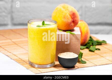 Smoothie mit Pfirsich und Minzblatt mit Stück Tuch auf weißem Backstein Hintergrund, horizontale Auflösung, gesunde Sommerdiät Stockfoto