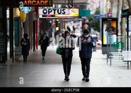 Melbourne, Australien, 4. August 2020. Ein Paar, das Gesichtsmasken trägt, schaut während der COVID-19 in Melbourne, Australien, auf seine Telefone im CBD. In nur 24 Stunden wird Melbourne in die Vollwirkung der COVID-19-Beschränkungen von Daniel Andrews Stage 4 verfallen. Einzelhändler, Dienstleistungen, Bauunternehmen und viele mehr werden morgen zum letzten Mal handeln, bevor sie für mindestens die nächsten 6 Wochen schließen müssen, wobei viele wahrscheinlich nie wieder eröffnet werden. Dies kommt, da über Nacht 439 neue Fälle aufgedeckt wurden, zusammen mit 13 Todesfällen, die alle Patienten in alten Pflegeeinrichtungen waren. Kredit: Dav Stockfoto