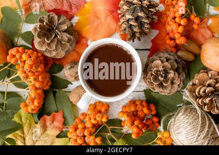 Gemütliche Tasse Kaffee und Herbstblätter auf weißem Holzhintergrund Stockfoto