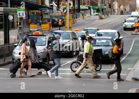 Melbourne, Australien, 12. August 2020. Fußgänger, die Masken tragen und ihre Einkäufe tragen, überqueren eine Kreuzung im Geschäftsviertel. Trotz der schwersten Einschränkungen in der Geschichte des Landes verzeichnete Melbourne am Mittwoch im Vergleich zu den Vortagen einen höheren Fußgängerverkehr, was darauf hindeutet, dass die Öffentlichkeit bereits während der COVID-19 in Melbourne, Australien, die Einschränkungen ihrer Freiheiten ermüdet. Victoria verzeichnete 21 weitere COVID-bedingte Todesfälle und 410 neue Fälle, was seinen tödlichsten Tag seit Beginn der Pandemie markiert. Kredit: Dave Hewison/Speed Media/Alamy Live Nachrichten Stockfoto