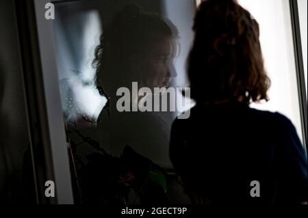 Berlin, Deutschland. Juli 2021. ILLUSTRATION - EINE Frau steht an einem Fenster in ihrer Wohnung. (Posed Scene) Quelle: Fabian Sommer/dpa/Alamy Live News Stockfoto