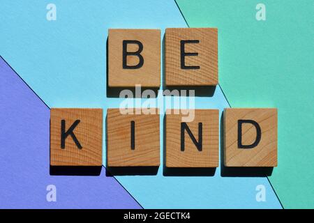 Seien Sie freundlich, positive Wörter in hölzernen Buchstaben Alphabet isoliert auf buntem Hintergrund Stockfoto