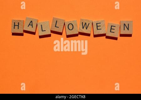 Halloween, Wort in hölzernen Buchstaben Alphabet isoliert auf orangefarbenem Hintergrund als Banner Überschrift mit Platz für Kopie Stockfoto