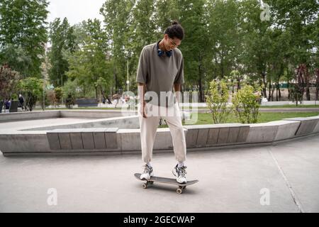 Junger afroamerikanischer Mann, der im Park Skateboard reitet Stockfoto