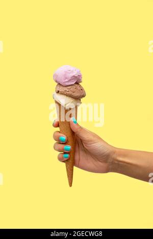 Die Hand der Frau hält ein Eis auf gelbem Hintergrund Stockfoto