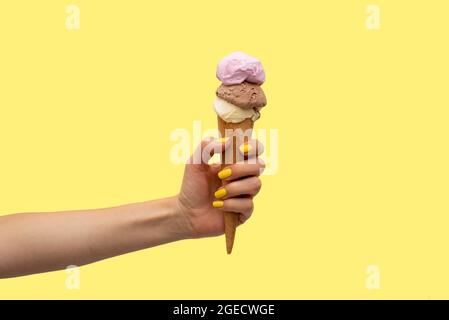 Die Hand der Frau hält ein Eis auf gelbem Hintergrund Stockfoto
