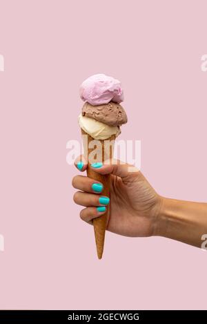 Die Hand der Frau hält ein Eis auf einem rosa Hintergrund Stockfoto