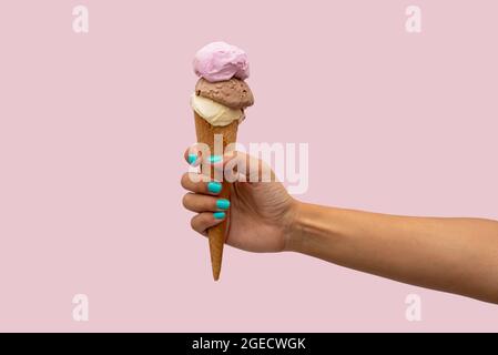 Die Hand der Frau hält ein Eis auf einem rosa Hintergrund Stockfoto
