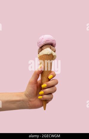 Die Hand der Frau hält ein Eis auf einem rosa Hintergrund Stockfoto
