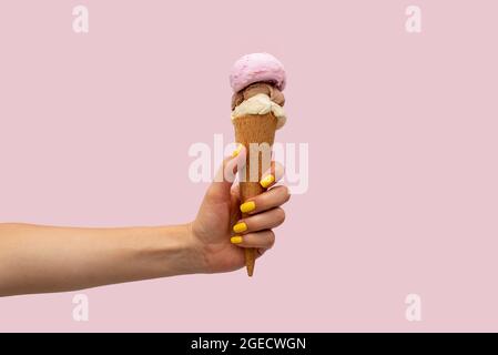 Die Hand der Frau hält ein Eis auf einem rosa Hintergrund Stockfoto