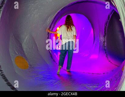 Architekten von Air's Tourenbauwerken in Blackburn, Lancashire, Großbritannien. August 2021. Zoe Felix erforscht in einem riesigen Ballon die sich verändernden Lichtmuster, die sich durch labyrinthartige Passagen und höhlenartige Kuppeln bewegen. Das Dodecalis Luminarium bietet Momente der Pause in meditativer Stille und ruhigem Staunen in den entlegensten Ecken der präzisionsgefertigten, „versteckten“ beleuchteten modularen Farbtunnels der Lichtarchitektur. Stockfoto